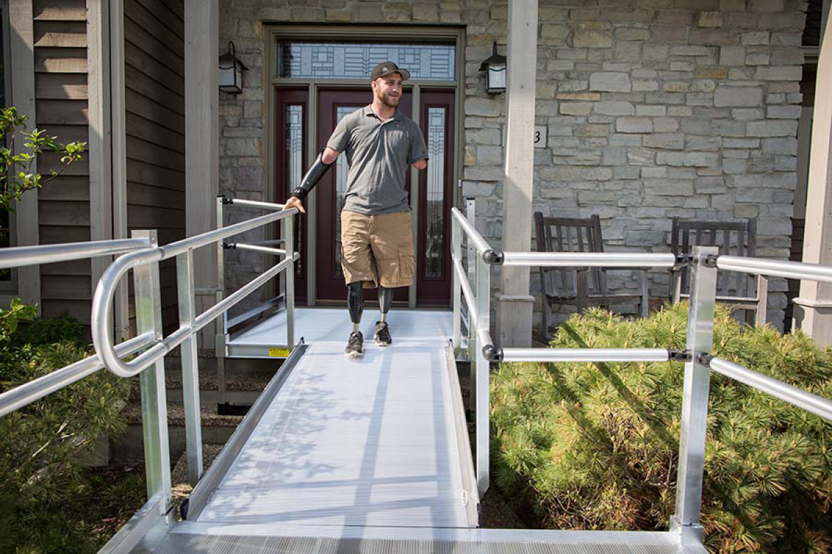 amputee using wheelchair ramp to access his driveway from his front door