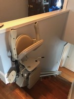 stair lift with components folded up at top landing of stairs in Havervill Massachuetts