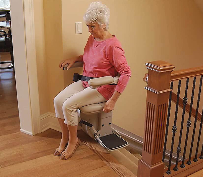 woman activates offset swivel seat to safely exit stairlift at top of stairs
