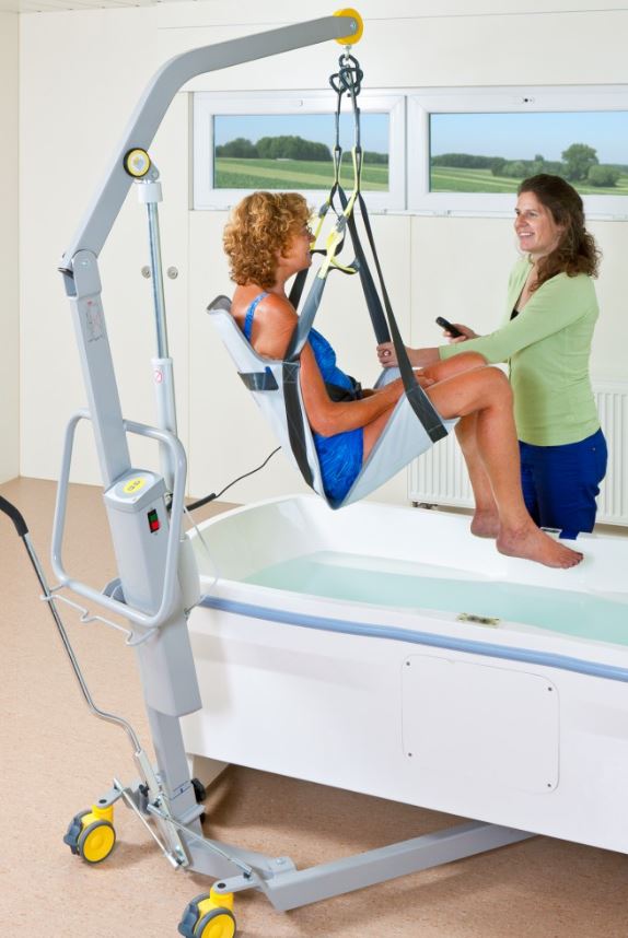 caregiver using mobile patient lift to help patient bathe