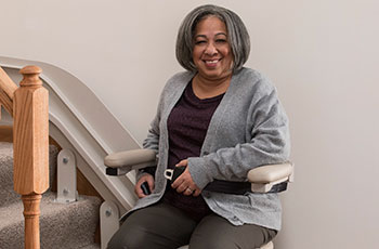 woman sitting on Lifeway Mobility stairlift fastens seat belt