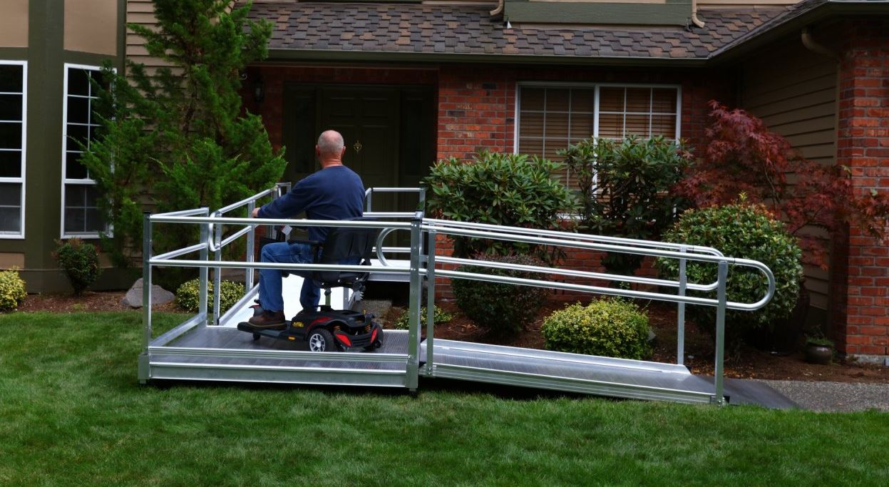 man riding scooter up wheelchair ramp to safely access his home