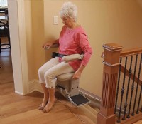 Bruno Elite Indoor Straight stairlift with lady showing swivel seat at top landing